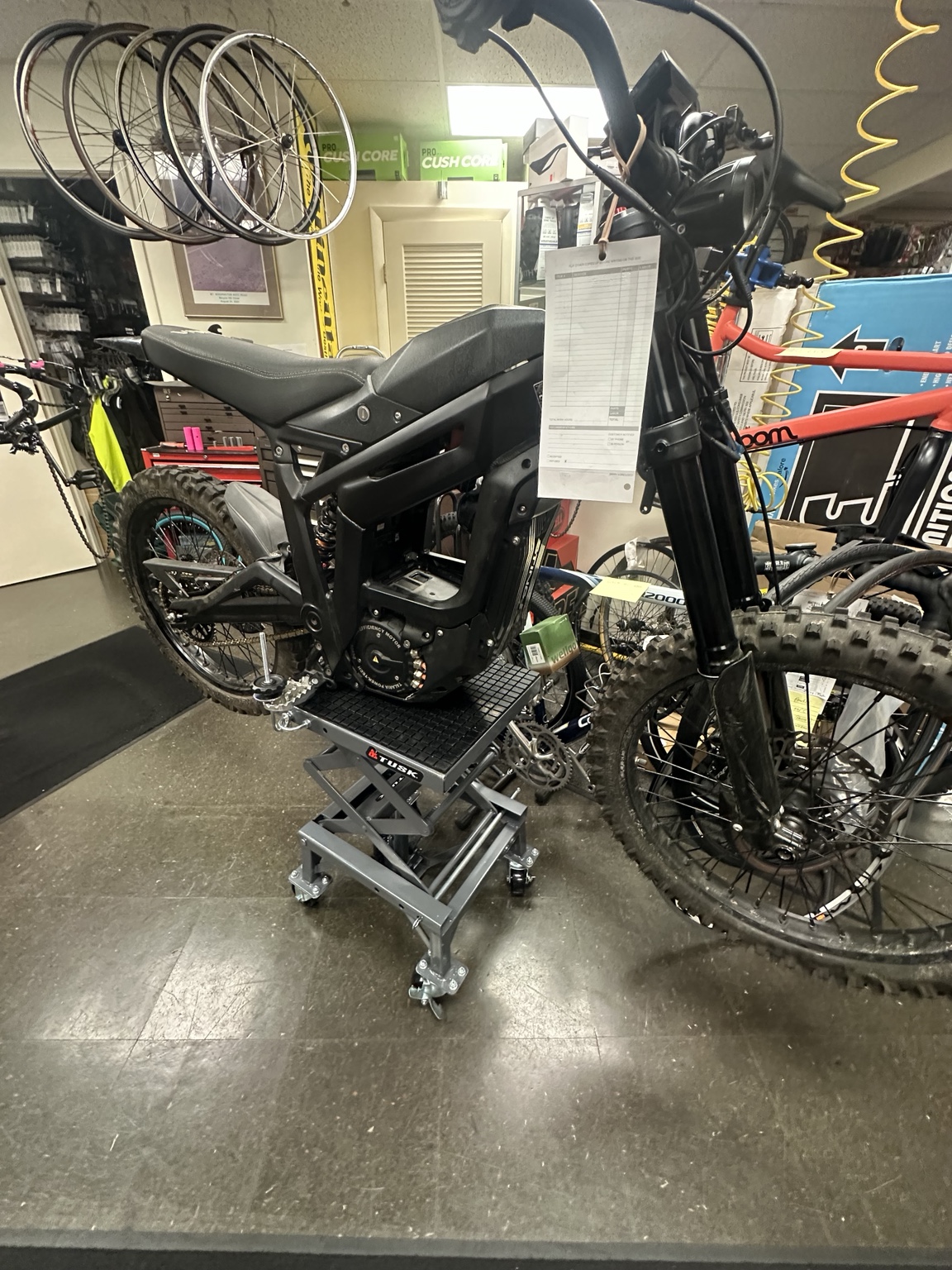 Talaria-style e-moto on service equipment inside Bicycles Plus